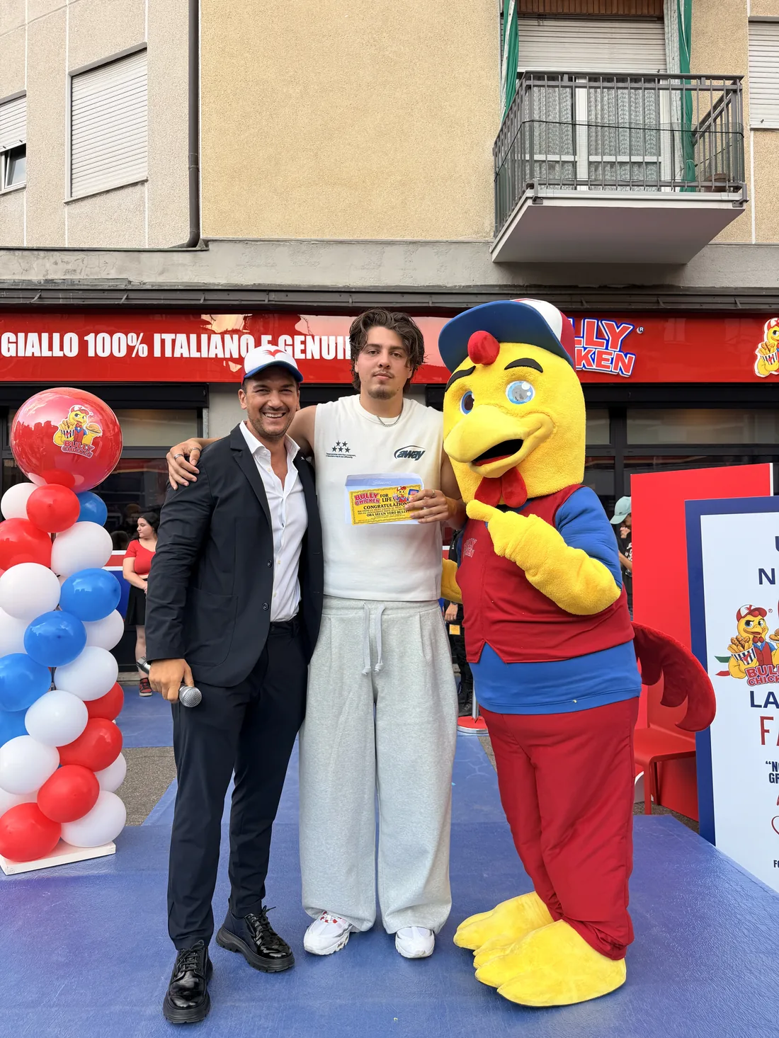 La mascotte Bully Chicken sul palco con il presentatore e un ospite con il Biglietto d'Oro