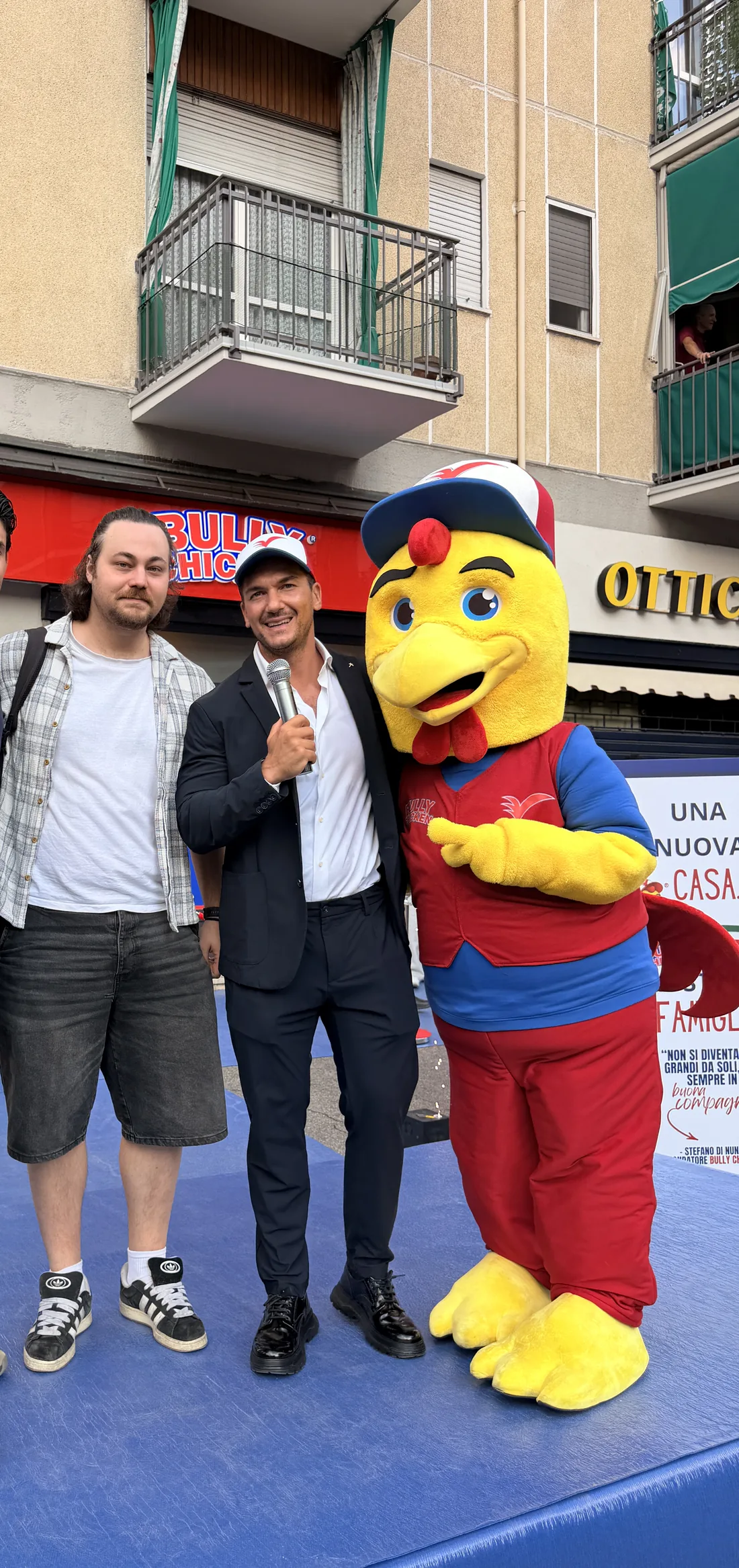 Ospiti sul palco con il presentatore e la mascotte davanti alla vetrina Bully Chicken
