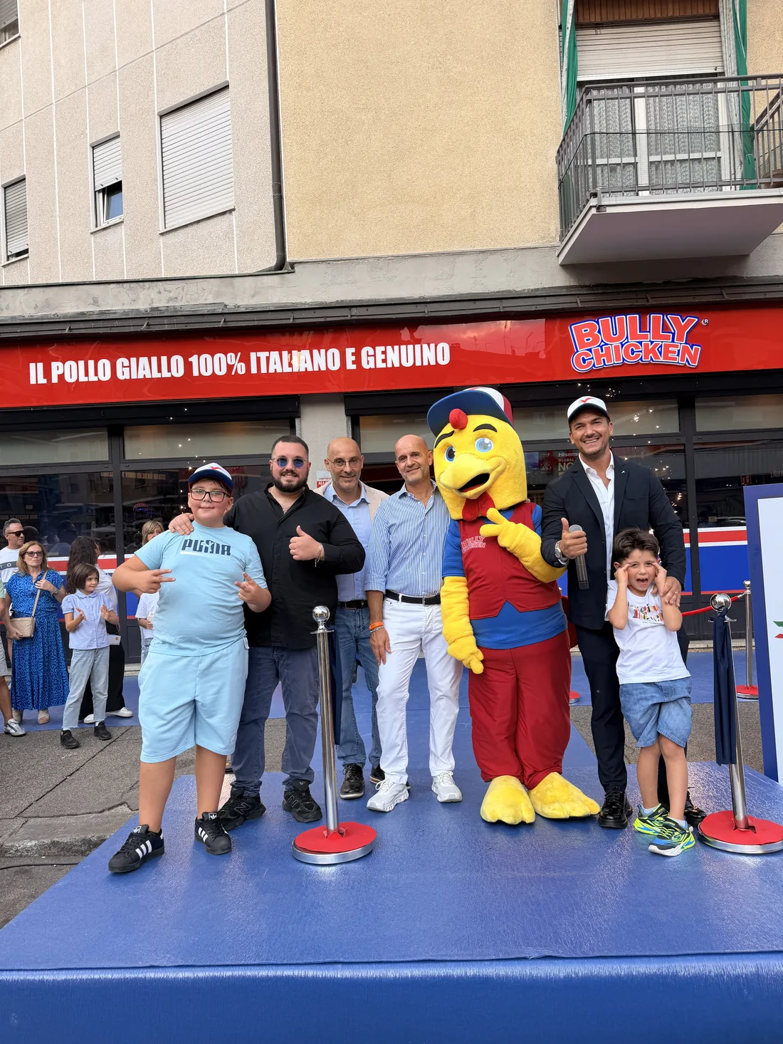 Foto di gruppo sul palco blu con la mascotte Bully Chicken